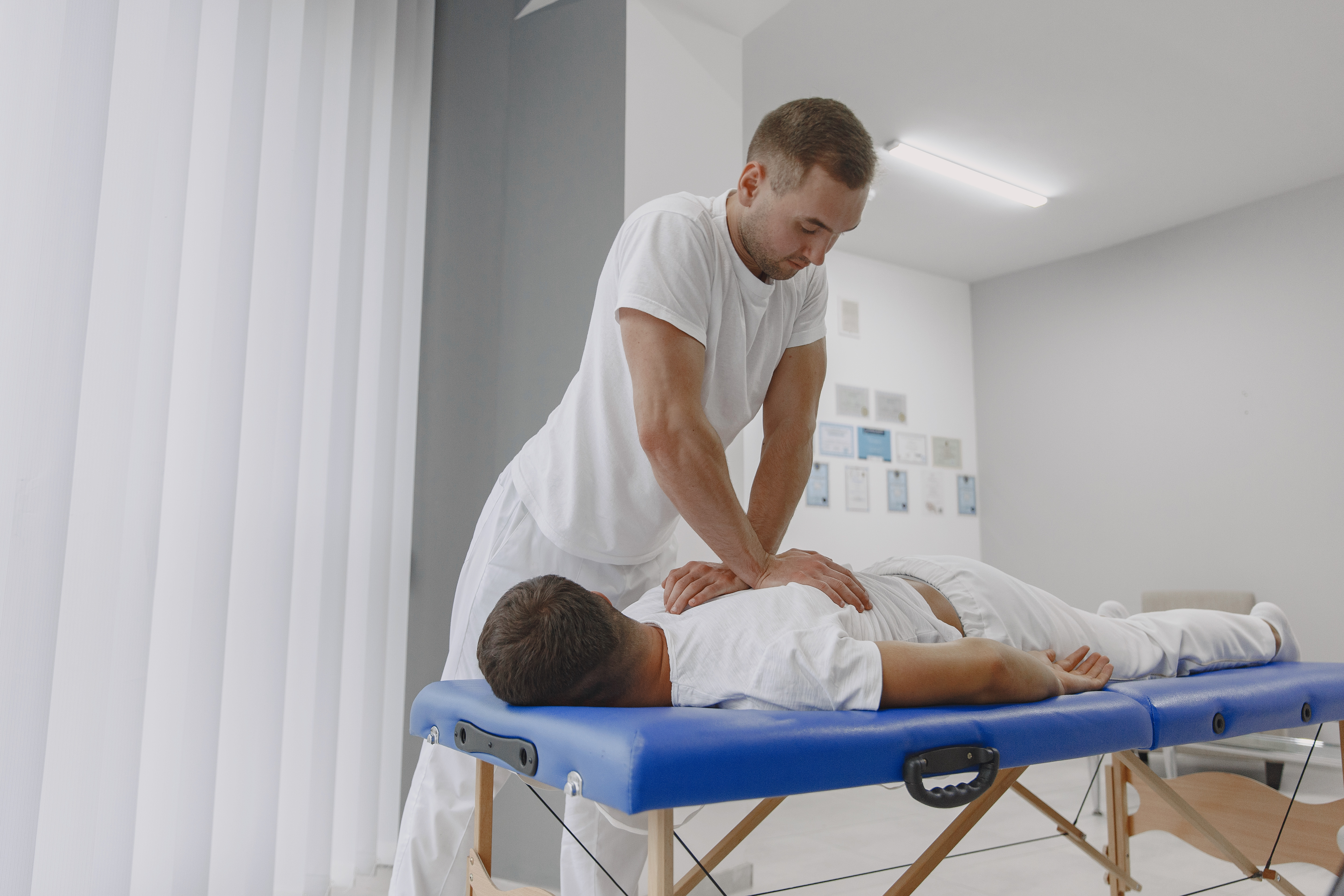 Male physiotherapist massaging man's back Man in the medical office. Physiotherapist is rehabilitating back.
